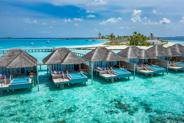 Aerial view of Maldives island, luxury water villas resort and wooden pier. Beautiful sky and ocean...