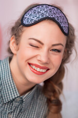 Young woman smiles and winks in a mask for sleep