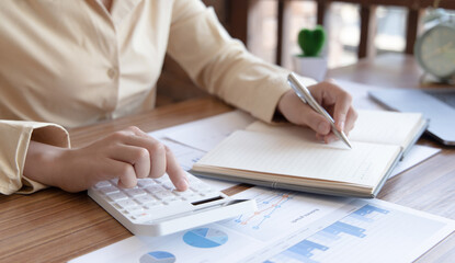 Head of accounting is recording the company's financial growth statistics using graphs as a reference for reviewing and analyzing the results, Taking notes and analyzing data graphs in office.