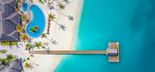 Beautiful aerial view of poolside and resort beach with wooden pier jetty. Luxurious tropical beach...
