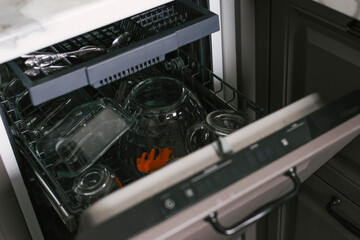Built-in dishwasher with open door in grey kitchen.