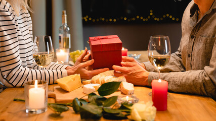 Cropped close up photo of lovers` hands giving each other presents for anniversary or St. Valentines Day during romantic dinner