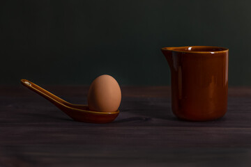 Easter photo concept. Egg, spoon and pitcher. Low key