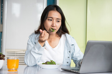 Eating healthy breakfast concept. woman holding dish of salad with variety vegetables and glass of orange juice on the floor in the morning at home.