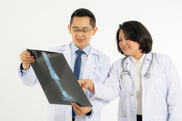 Two asian doctor looking at film x-ray head of patient and discussing surgery plan for cure disease.