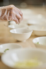 Chef using gloves while arranging bowls and plates