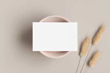 White business card mockup with a dried lagurus decoration on the beige table. 85x55mm	