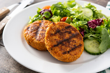 Delicious healthy chickpea burger and salad on wooden table