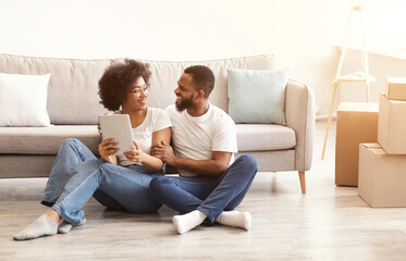 Obraz premium African Couple Using Tablet Sitting In New House After Relocation