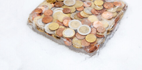 Frozen money in ice in winter snow. Euro coins, cash money frozen melt. Frozen Euro assets and financial crisis concept