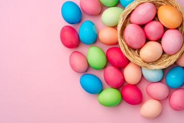 Painted Easter eggs in decorative nest on pink background