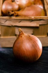 Brown onions in basket on wooden background.