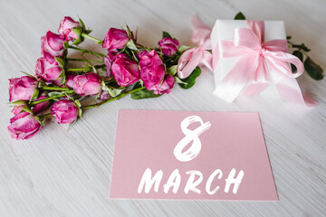 Composition of pink small roses, gift box, postcard on white wooden background. Happy Birthday....