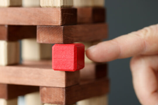 Wooden tower made of wooden brown cubes from which red cube is taken