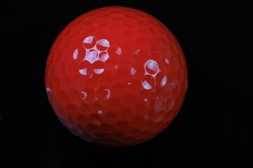 Close-up of a red golf ball on a black background