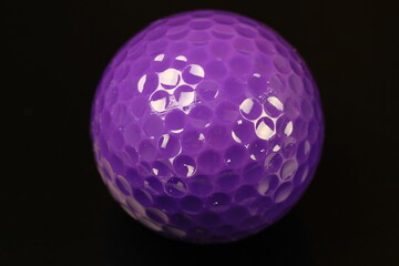 Close-up of a purple golf ball on a black background