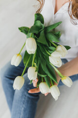 A bouquet of white tulips in the hands of a girl. Spring mood, clean and laconic.