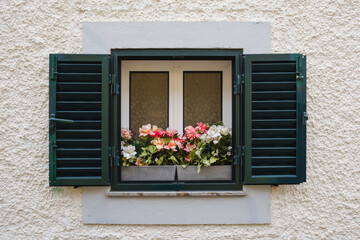 Fototapeta na wymiar window in the wall with blinders open and a vase with flowers