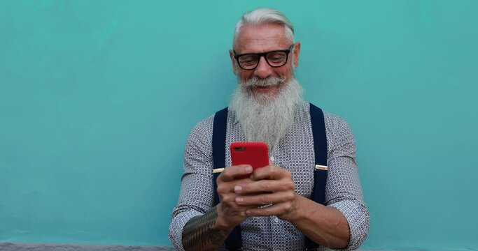 Trendy senior man using smartphone app - Tech and joyful elderly lifestyle concept