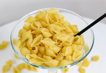 Shell shaped pasta is poured into a cocktail glass with a drinking straw. Creative photo.