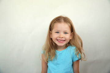Cute little girl shows emotions on a white background in a T-shirt. Simple beauty. High quality photo