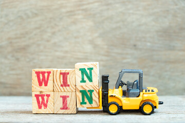 Toy forklift hold letter block n to complete word win win on wood background
