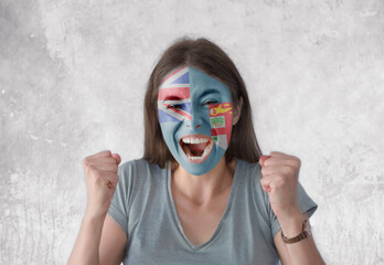 Young woman with painted flag of Fiji and open mouth looking energetic with fists up