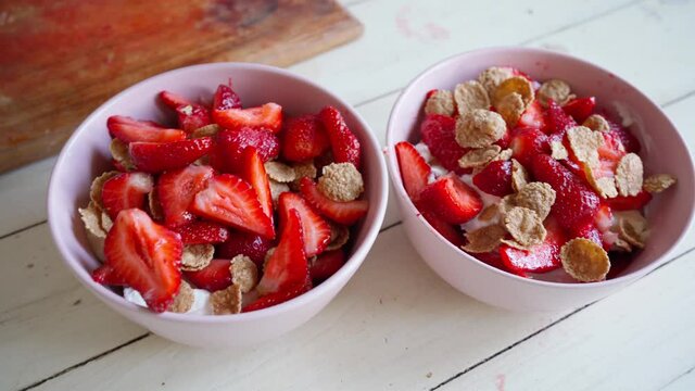 close up putting multigrain whole grain flakes in to bowl with cutted strawberry and yogurt. making healthy dietary fruit breakfast. healthy vegetarian food concept