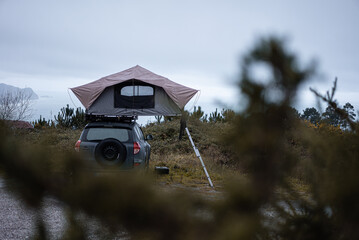 Car rooftop tent for camping on the roof rack of an off-road car by the lakeside © Stefan Bremer/Wirestock