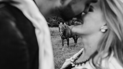  Love story of kissing couple. Handsome guy and blonde girl walking on the grass near the river and forest.