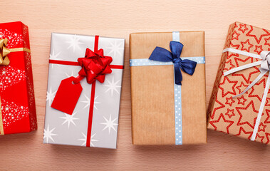 Different gifts packed with craft paper and colorful ribbons on wooden table.