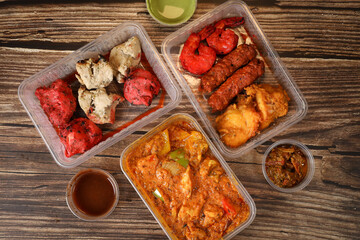 Top view of traditional Indian food in a plastic box on a wooden table. Indian fast food delivery at home. Eat at home.