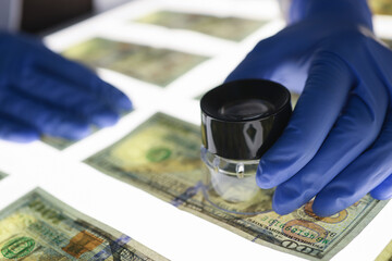 Expert checks authenticity of banknotes. Counterfeiting and types of fraud