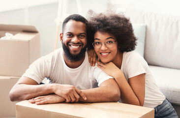 African Spouses Sitting Among Moving Boxes Hugging In New House