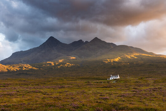 Beautiful golden light with dramatic dark clouds over Cuillin mountain range on the Isle of Skye, Scotland, UK.