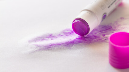 Glue pencil is applied to a sheet of paper. The purple glue disappears when it dries.