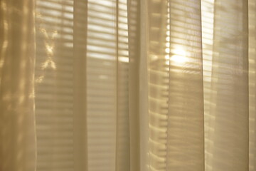 The sun shines through the white organza tulle and blinds.