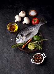 Dorado fish on the black stone   with lime, rosemary, pepper, tomato  and salt. Top view.
