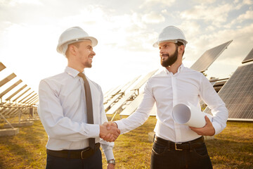 Male partners shaking hands on solar farm