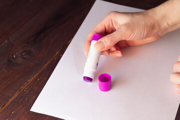 A person applies glue to a sheet of white paper to glue