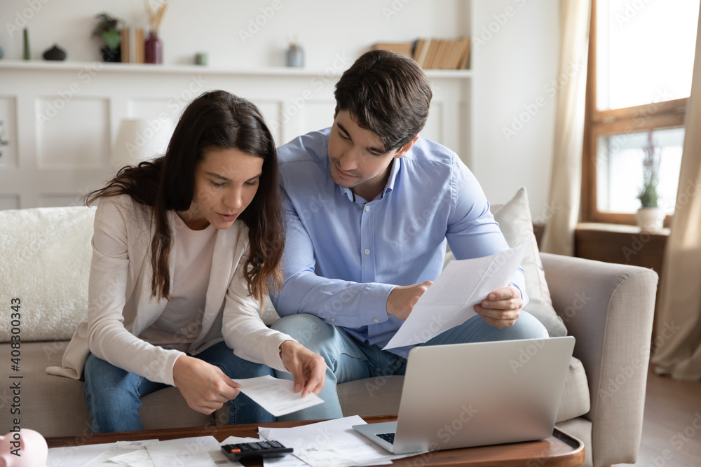 Wall mural close up young couple checking mortgage or loan agreement, financial documents together, using lapto