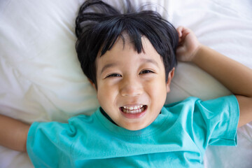 Authentic close up of happy kid in a bed. Concept of new generation, family, parenthood, authenticity, Son.