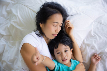 Authentic close up of happy mother and her son in a bed. Concept of new generation, family, parenthood, authenticity, connection.