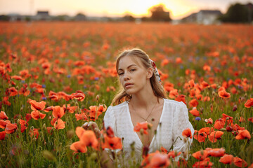 Naklejka premium portrait of a girl in a white dress in a field of red poppies