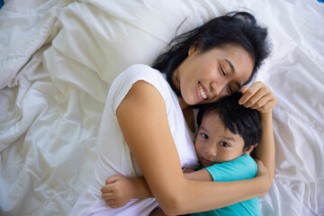 Authentic close up of happy mother and her son in a bed. Concept of new generation, family, parenthood, authenticity, connection.