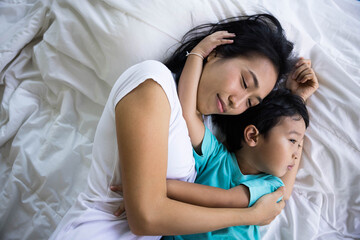 Authentic close up of happy mother and her son in a bed. Concept of new generation, family, parenthood, authenticity, connection.