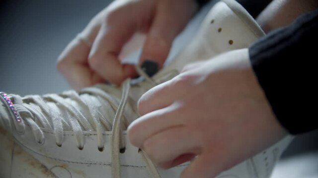 Ice skating - woman ties shoelaces on white skates