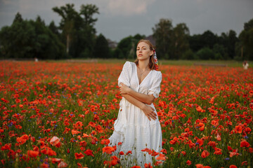 Fototapeta na wymiar woman in white dress in a field of poppies