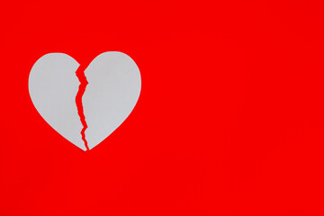 White broken heart on red background with copy space.