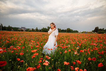 girl in a white dress in a field of red poppies